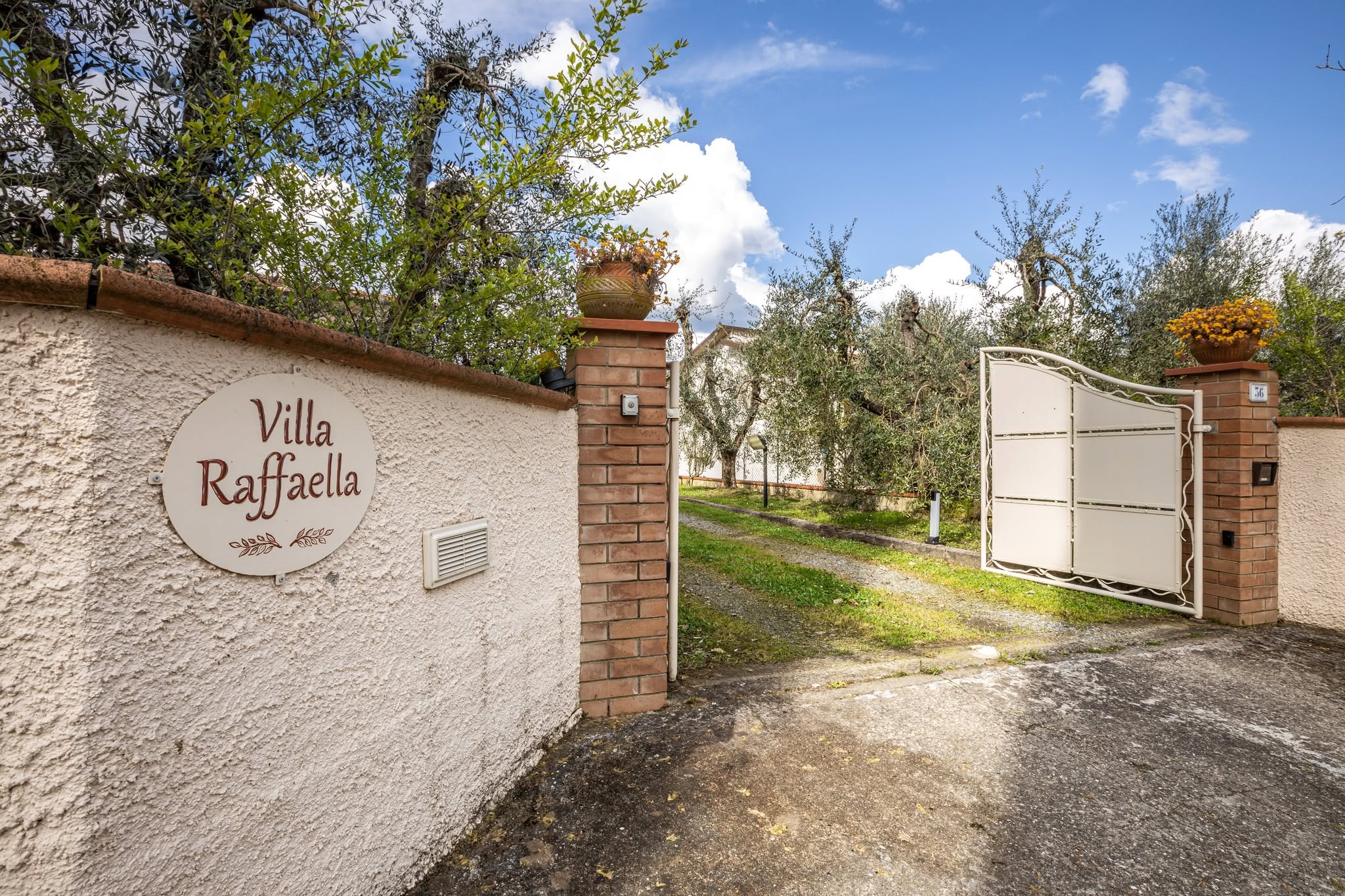 A tasteful, informative vignette suggesting booking details for a luxury Tuscan vacation rental, without using text. A polished wooden console table in the villa’s entrance holds a neatly arranged still life: a leather-bound guest book open to a blank page, an antique-style room key with a small metal tag resting beside it, and a folded map of Tuscany with Terricciola subtly visible. A ceramic bowl of fresh lemons and a small sprig of olive leaves add color and natural texture. Soft indoor lighting from an unseen wall sconce casts warm, intimate shadows. Photographic realism, shot from above with a carefully balanced composition, creating an atmosphere of anticipation and organization, symbolizing check-in, reservations, and the promise of a well-managed stay at Villa Raffaella.